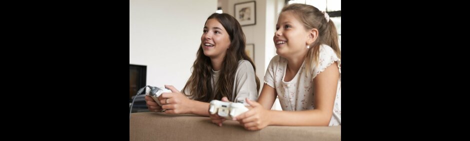 2 lächelnde Mädchen spielen mit Controllern (StMAS/Laura Freiberger)